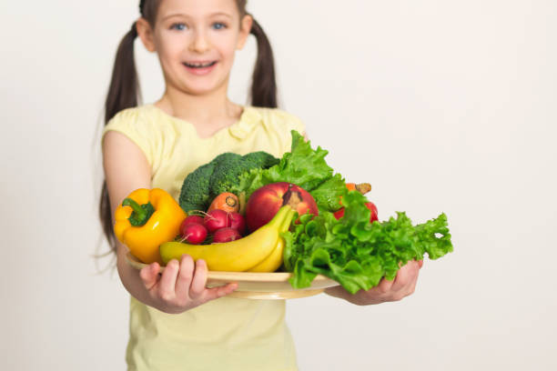 istock Cute little smiling girl holding fresh vegetables 947920610