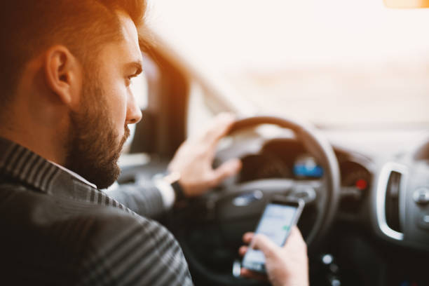 istock Attractive bearded man texting while driving an expencive car in a sunny weather. 947925668