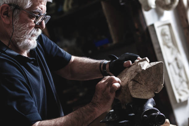 Senior man working on his wooden sculpture in his workshop.