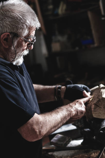istock Senior man working on his wooden sculpture in his workshop. 947948378