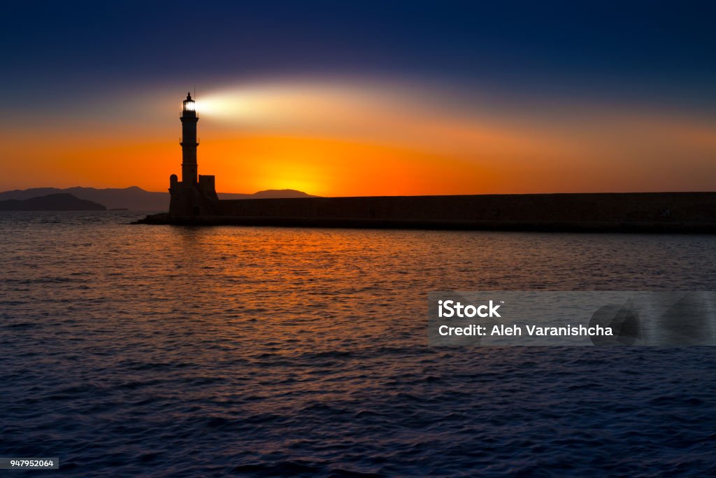 A beautiful night sky behind a shining lighthouse. Crete, Greece A beautiful night sky behind a shining lighthouse. Chania, Crete, Greece Lighthouse Stock Photo
