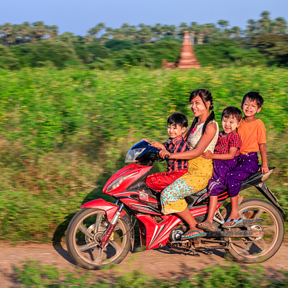 Burmese children with thanaka riding motorbike near the ancient temples of Bagan, Myanmar (Burma)