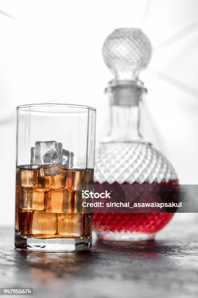 Bottle Whiskey And Glass Of Whiskey With Ice And Light Blurred Background Stock Photo - Download Image Now