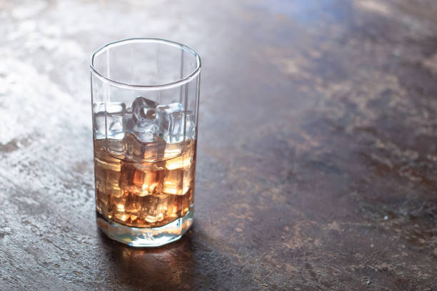 istock Glass of whiskey with ice on black background 947955686