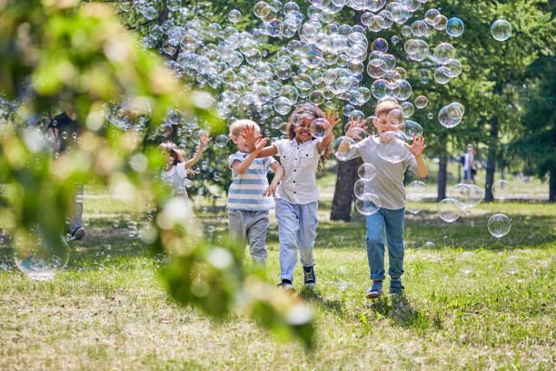 istock Cheerful Kids Playing with Soap Bubbles 947959250