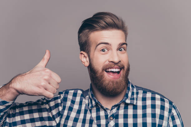 istock Young happy stylish bearded guy showing thumb up 947960142