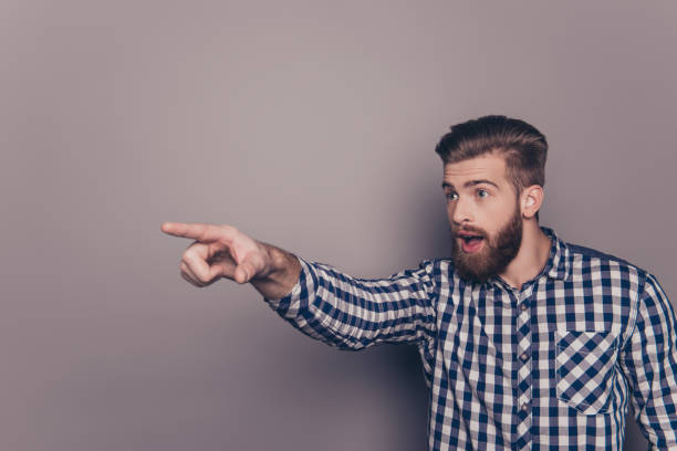 istock Amazed young bearded stylish man pointing with finger 947970492