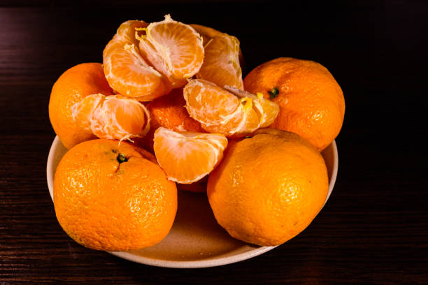 istock Plate with mandarins on a dark wooden table 947972198