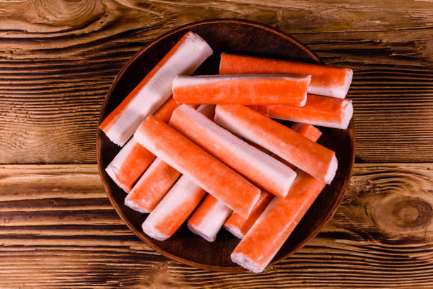 istock Ceramic plate with crab sticks on wooden table. Top view 947972278