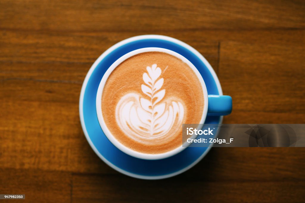 A cup of cappuccino on table. A cup of cappuccino with beautiful latte art on wooden table. Top view, morning mood. Top - Garment Stock Photo