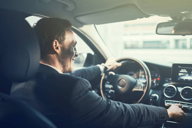 Smiling young businessman changing radio stations while driving his car