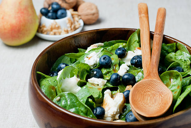Spinach salad with berries and chicken in a wooden bowl