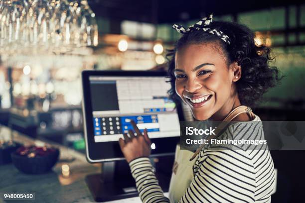 Smiling African Waitress Using A Restaurant Point Of Sale Terminal Stock Photo - Download Image Now