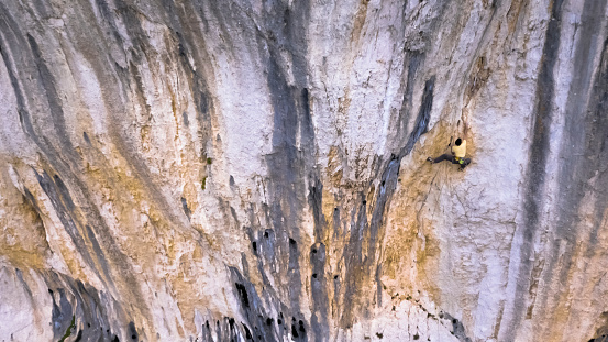 Male rock climber ascending rugged cliff.