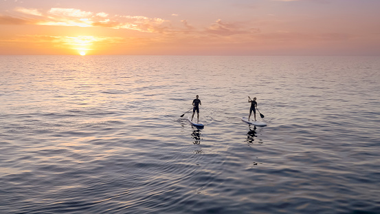 Man and woman doing standup paddling in sea