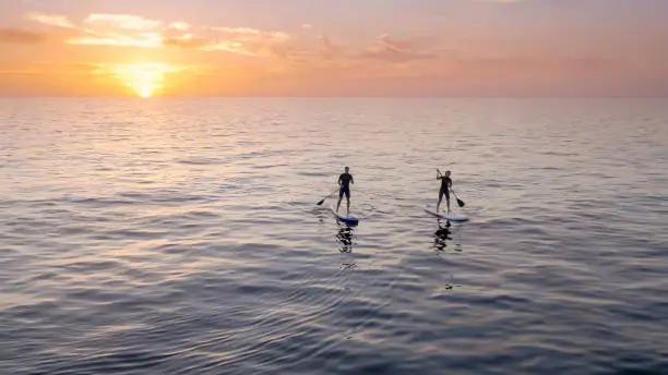 Photo of Man and woman doing standup paddling in sea