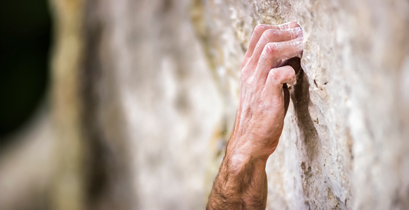 Close-up of man's hand on rugged cliff.