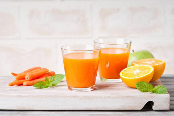 istock Glasses with carrot juice, apple, sliced orange and mint leaf 948033942