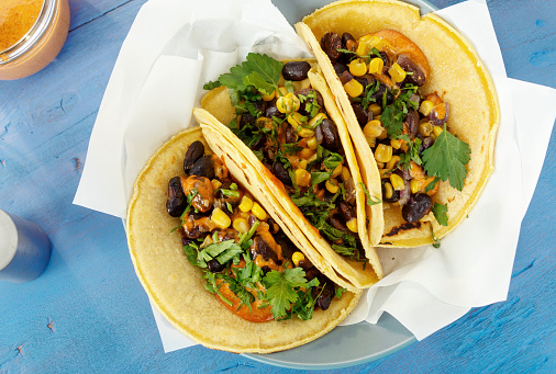 Vegetarian healthy corn tortillas with vegetables on wooden table, top view