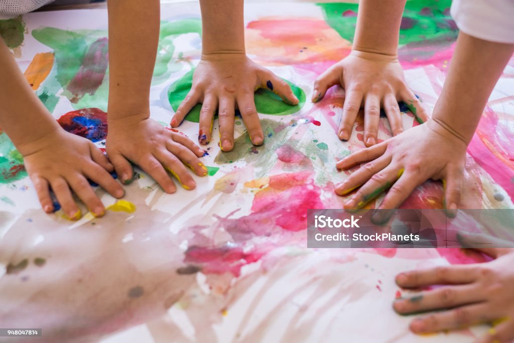 Close up colored kids hands on the table Close up children hands in circle on the table painted with water colors Child Stock Photo