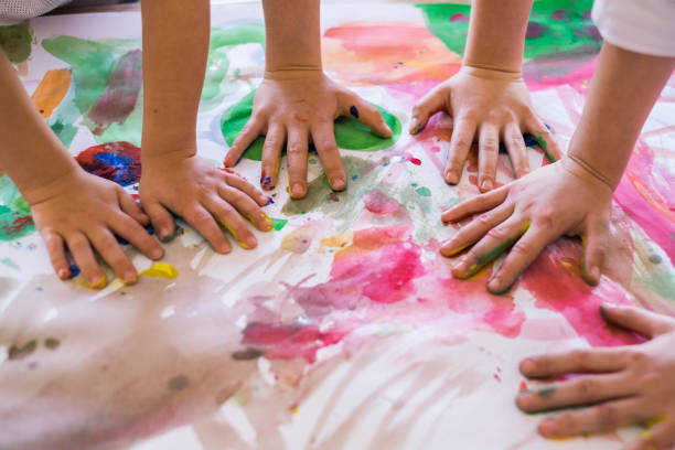 Close up colored kids hands on the table Close up children hands in circle on the table painted with water colors preschool building stock pictures, royalty-free photos & images