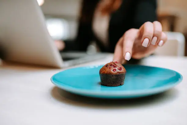 Photo of Close-up image of female hand taking delicious muffin with berries.