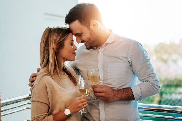 изображение прекрасной пары, пьюей белое вино во время объятий. - toast women white horizontal стоковые фото и изображения