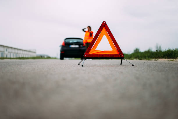 istock Red warning triangle on asphalt road. Woman catching car on road. 948056798