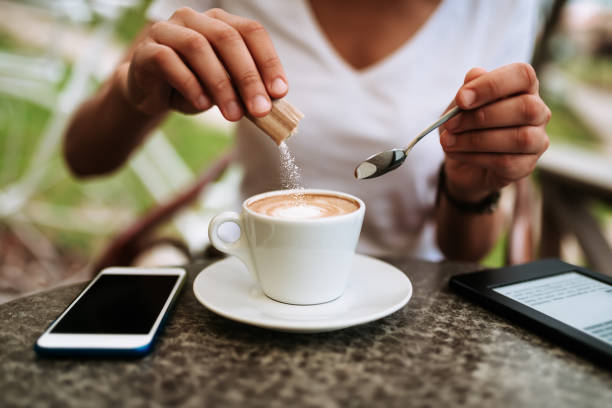 giovane donna che aggiunge zucchero bianco al caffè. - sugar foto e immagini stock