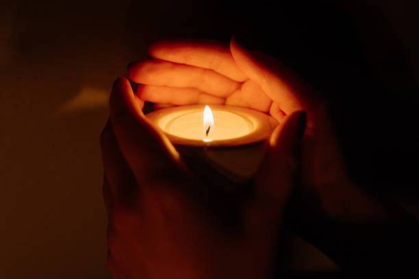istock Woman's hands holding a burning candle on dark background. Close-up. 948069026