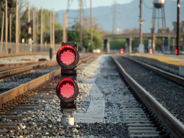 A railroad color position light sits ground level flashing red stop lights with space to right