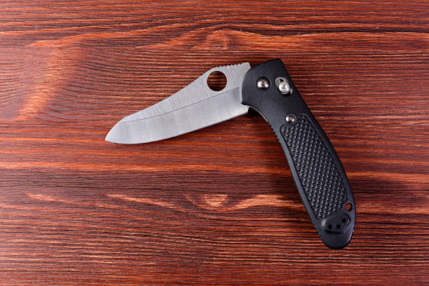 istock Folding knife with black handle on wooden backgound 948104450