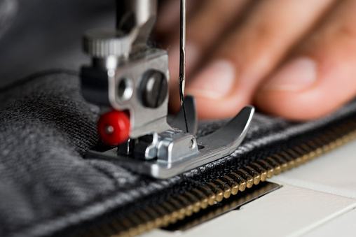 a seamstress sews a piece of material on a sewing machine
