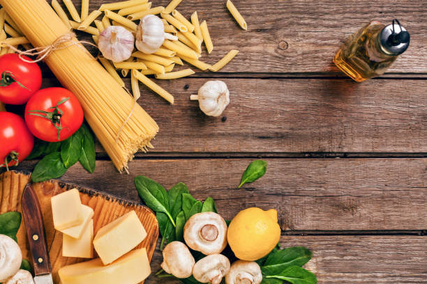 istock Ingredients for spaghetti with basil, tomatoes, cheese on wooden background, top view, place for text 948107100