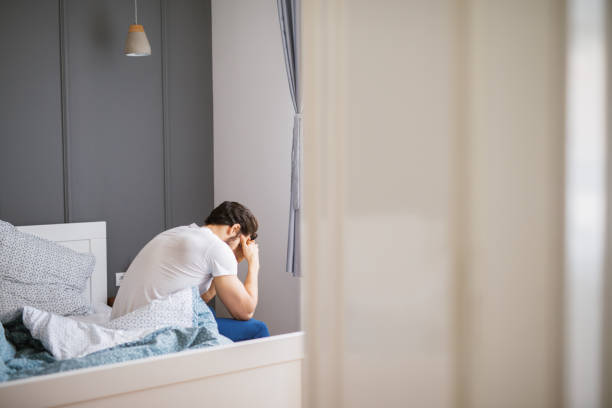 istock Rear view of a heartbroken young guy sitting on a bed. 948115832