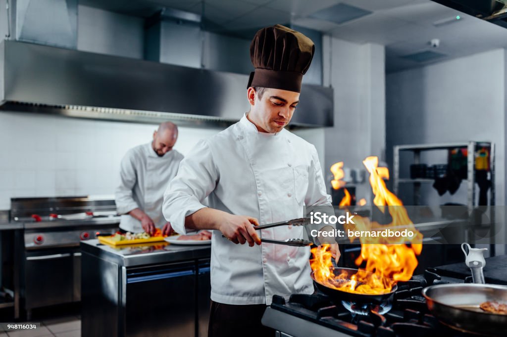 He;s got a special cooking skill Shot of two young chefs in the kitchen preparing food Chef Stock Photo
