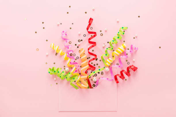 Party confetti & sequins explosion from envelope on pink Confetti & sequins explosion. Opened envelope with festive streamers on pink background. Party Invitation concept. Flat lay, minimal style. streamer photos stock pictures, royalty-free photos & images