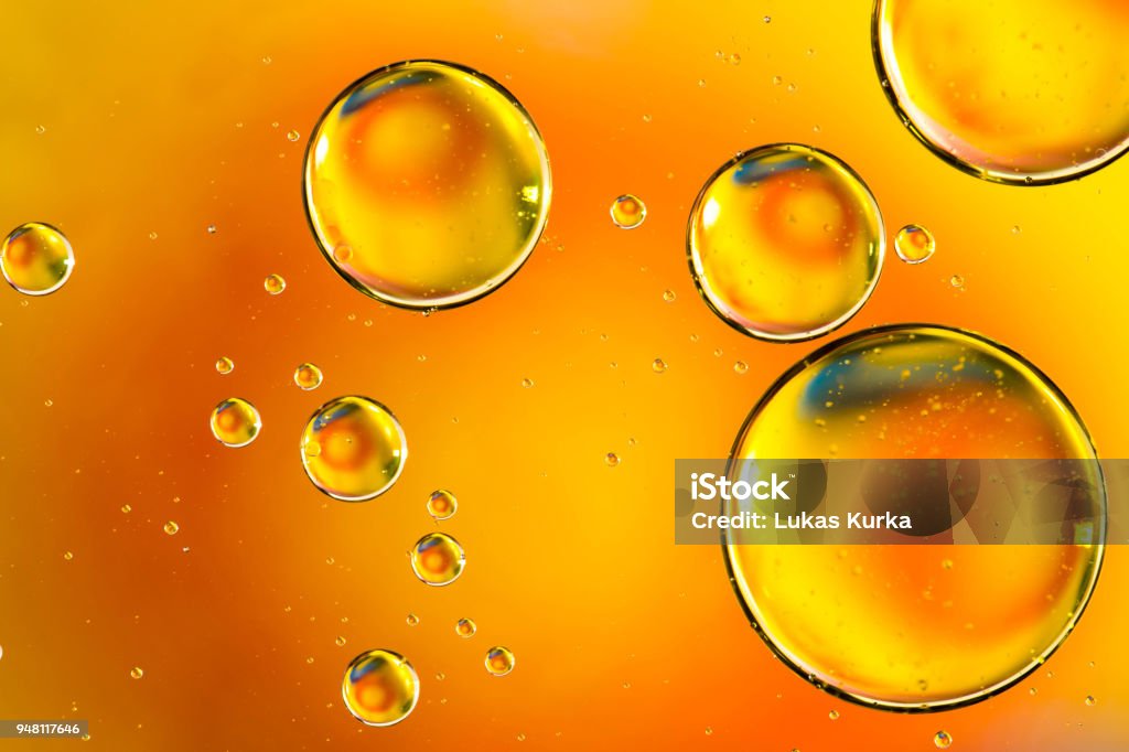 Oil drops in water, bubbles on orange abstract background Cooking Oil Stock Photo