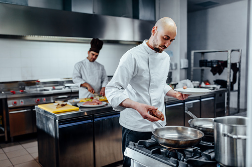 Shot of two young cooks preparing food in the kitchen