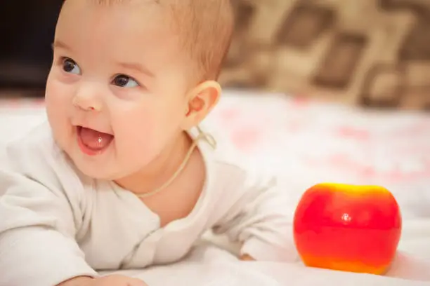 month old baby lying inbed with apple