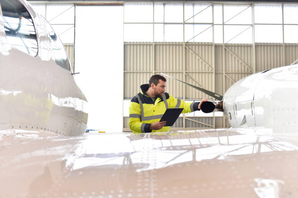 mecánico de aviones inspecciona y comprueba la tecnología de un avión en un hangar en el aeropuerto - garlopa fotografías e imágenes de stock