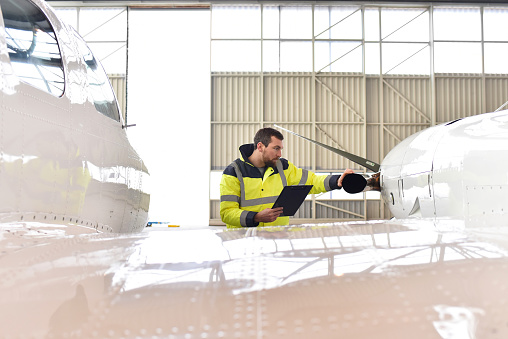 Aircraft mechanic inspects and checks the technology of a jet in a hangar at the airport