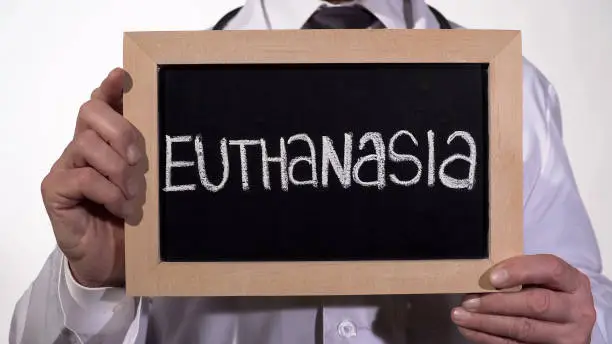 Photo of Euthanasia written on blackboard in doctor hands, controversial social problem