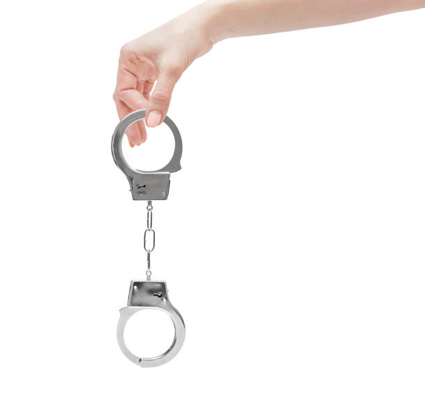 istock Female's hand holding handcuffs. Isolated on white. 948164872
