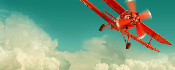 Red biplane flying in the cloudy sky