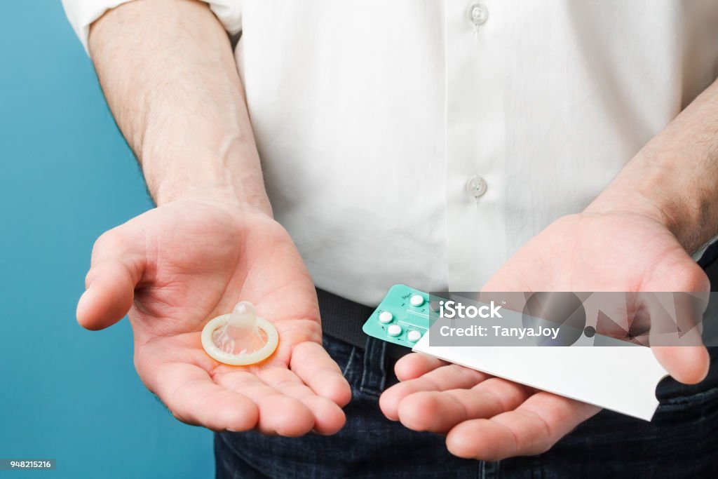Pilules et des préservatifs dans les mains des hommes - Photo de Adulte libre de droits