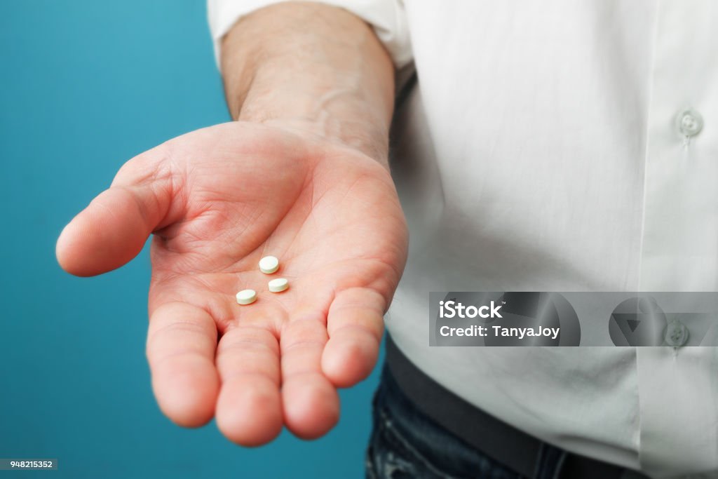 Pills in hands of men Three white tablets in hands of men Men Stock Photo