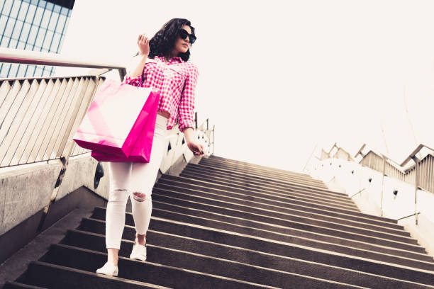 uma garota jovem e bonita que sobe as escadas depois de fazer compras. - christmas emotional stress shopping holiday - fotografias e filmes do acervo