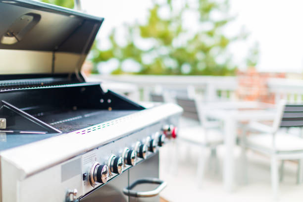 Six burner outdoor gas grill with open lid on backyard.