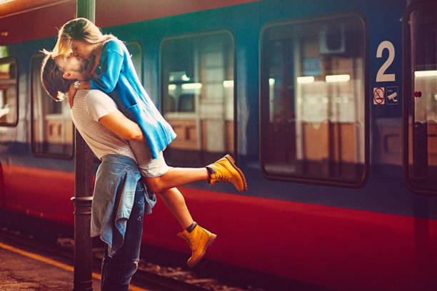 giovane appassionato e donna che si bacia accanto al treno alla stazione ferroviaria - attività romantica foto e immagini stock